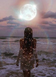 a woman standing on top of a beach next to the ocean under a full moon