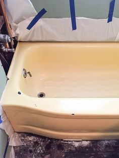 an old bathtub with blue tape on it and the tub is being worked on