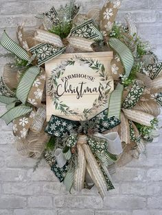 a christmas wreath hanging on the side of a brick wall with ribbons and bows around it