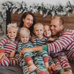 a family in matching christmas pajamas posing for a photo on the bed with their children