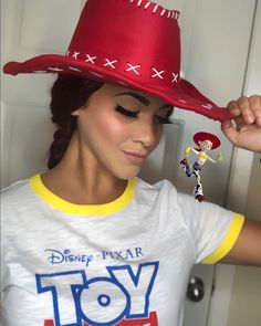 a woman wearing a red hat and yellow t - shirt with toy story characters on it