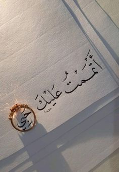 an arabic calligraphy written on paper with a gold ring