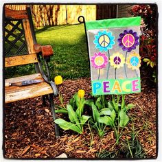 a peace sign sitting on top of a patch of grass next to a wooden bench