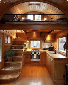 a kitchen with wooden floors and stairs leading up to the loft