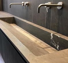 a bathroom sink with two faucets on the wall and marble counter top next to it