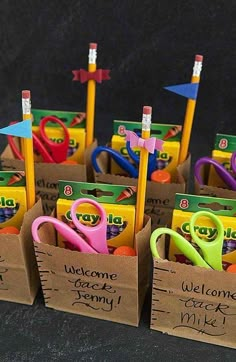 small cardboard boxes filled with different types of scissors and pencils, each containing the word welcome