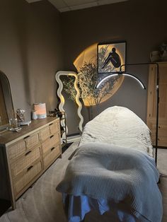 a bedroom with a bed, dresser and mirror in the corner next to each other