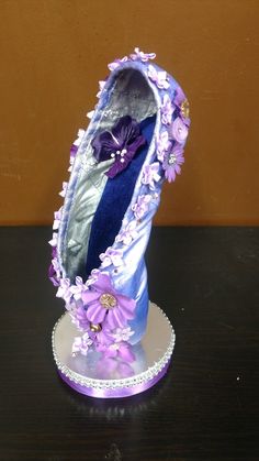 there is a purple ballerina shoe with flowers on the top and bottom, sitting on a table