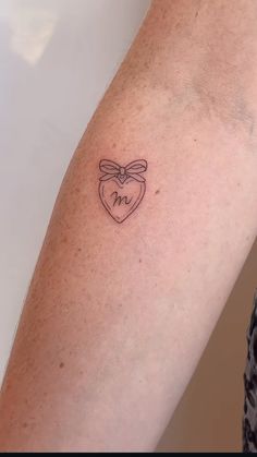 a woman's arm with a small heart tattoo on it