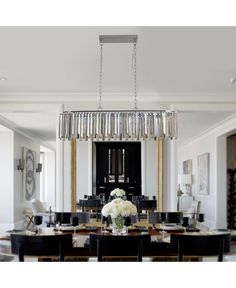 a chandelier hanging from the ceiling in a dining room with black table and chairs