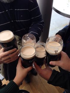 several people are holding up glasses of beer