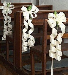 two wooden pews decorated with ribbons and flowers