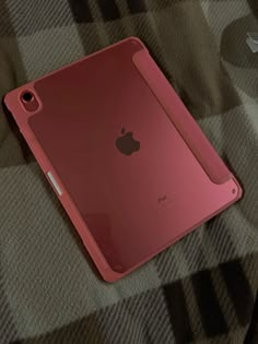 an apple ipad case sitting on top of a plaid cloth covered tablecloth, with the cover partially open