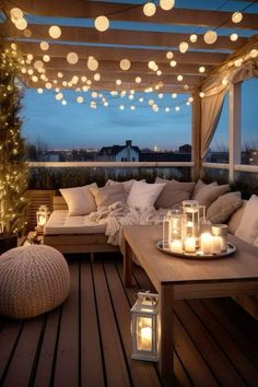 an outdoor living area with lights strung from the ceiling and pillows on the couches