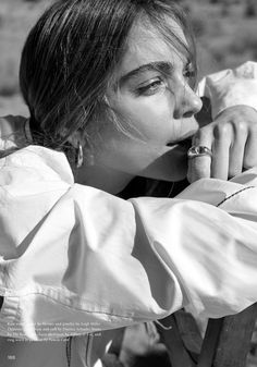 a woman sitting on top of a wooden bench wearing a white shirt and silver rings