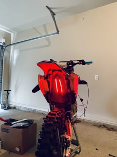 a red motorcycle parked in a garage next to a tool box and wrench on the floor