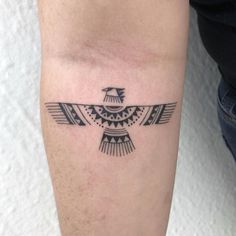 a black and white bird tattoo on the left leg, with an arrow in it's center