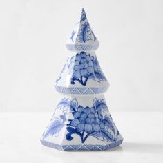 a blue and white christmas tree with flowers on it's sides is shown in front of a plain background