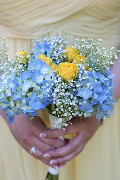 a bouquet of blue and yellow flowers in someone's hands