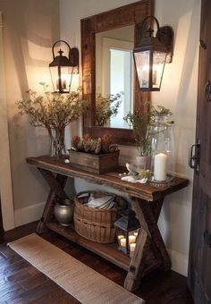 a wooden table topped with vases filled with flowers next to a wall mounted mirror