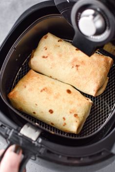 two burritos are being cooked in an air fryer