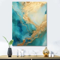 an abstract painting in gold and teal tones on a wall above a console table