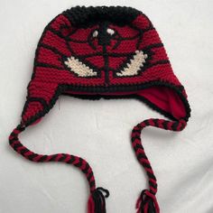 a crocheted red and black hat with white eyes