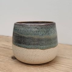 a close up of a cup on a wooden table with a white wall in the background