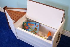 a toy chest with books in it on the blue carpeted floor next to a wall