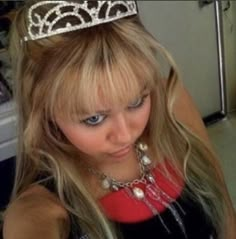 a woman wearing a tiara in a room with other items on the floor and walls