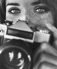 a woman with freckles on her face holding up a camera