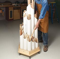 a man standing next to a large stack of pipes in a room with wooden shelves