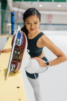 a woman standing next to a skateboard on top of a wooden board racket