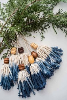 some tassels are hanging from a branch with pine cones and beads on them