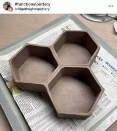 three hexagonal trays sitting on top of a paper with newspaper underneath them