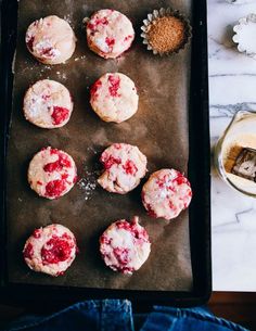 there are many strawberry muffins on the baking sheet next to a glass of milk