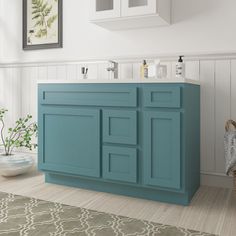 a bathroom with a blue cabinet and white fixtures in the wall, along with a rug on the floor