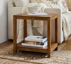 a coffee table with books on it in front of a white couch and throw pillows