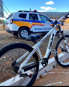 a police bike parked next to a curb with a van in the back ground behind it