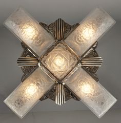 a ceiling light with four lights on each side and an intricate design in the middle