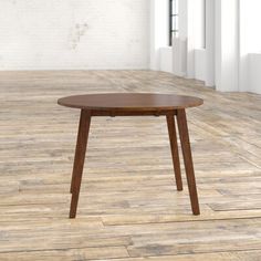 a wooden table sitting on top of a hard wood floor next to a white brick wall