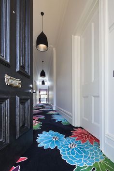 the hallway is decorated in black and white with colorful flowers on the carpet, along with hanging lights