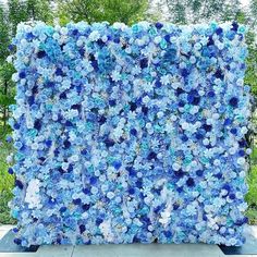 a large blue and white flowered wall in front of trees