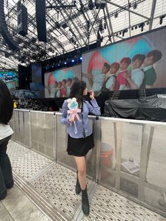 a woman is standing on a platform with her back to the camera and holding a stuffed animal