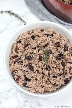 a white bowl filled with rice and raisins on top of a marble counter