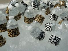 several plastic water bottles with zebra print lids and caps on top of ice cubes