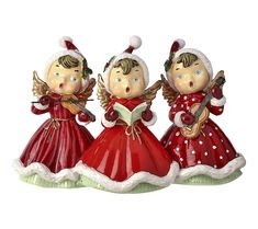 three little angel figurines with musical instruments in red and green dresses, one holding a book while the other is singing