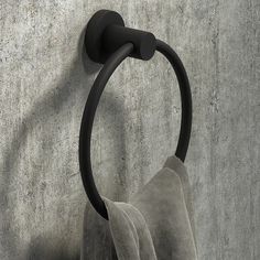 a towel hanging on the wall next to a toilet paper holder with a black handle