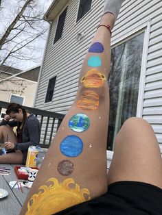 a woman's legs with solar system painted on them and people sitting in the background