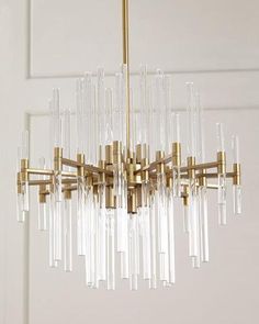 a chandelier hanging from the ceiling with clear glass tubes and gold fixtures on it